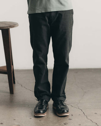 fit model with his hand in his pocket wearing The Democratic Foundation Pant in Organic Faded Black
