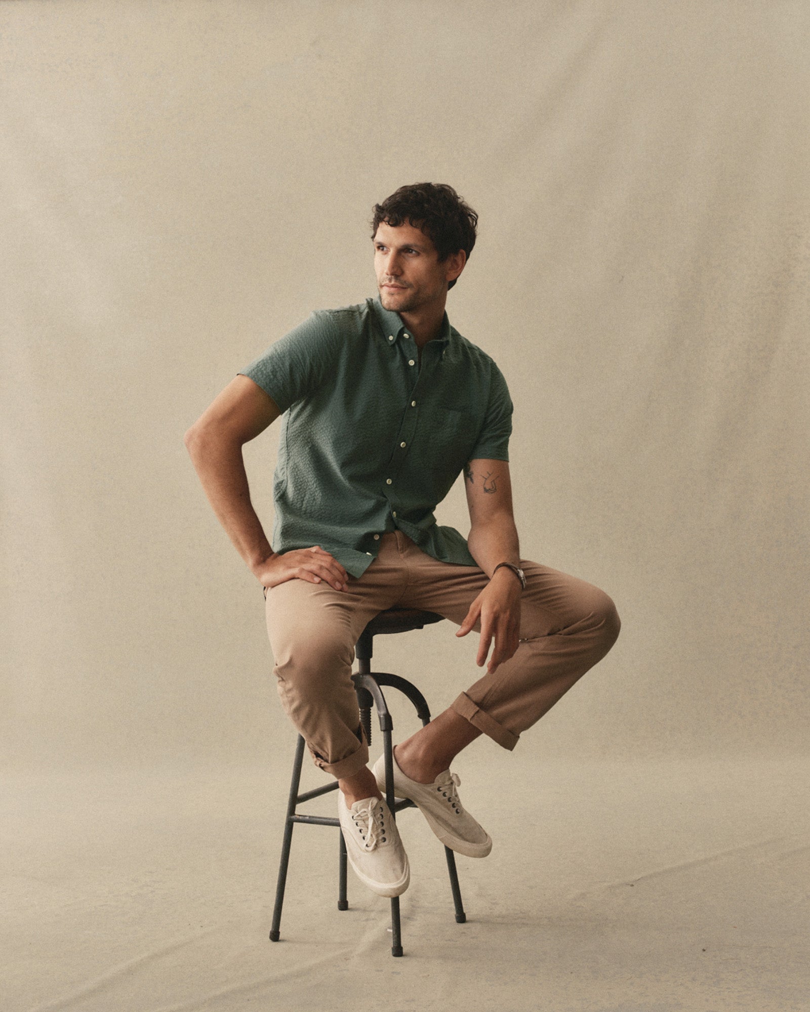 fit model sitting wearing The Short Sleeve Jack in Deep Sea Seersucker, Wovens by Taylor Stitch