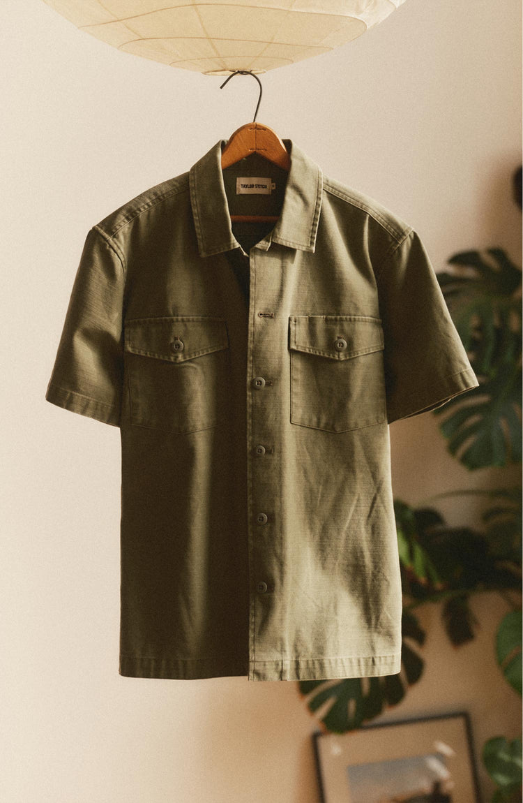 editorial image of The Short Sleeve Surplus Shirt in Field Olive Reverse Sateen  hanging