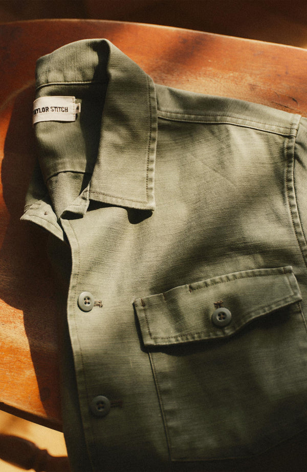 editorial flatlay of The Short Sleeve Surplus Shirt in Field Olive Reverse Sateen on a chair