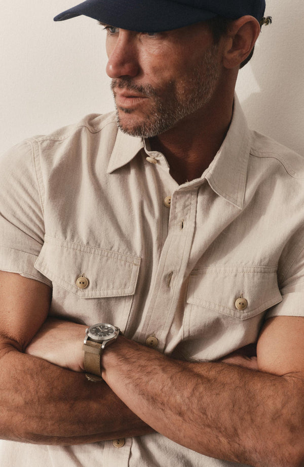 fit model with his arms crossed wearing The Short Sleeve Crew Shirt in Natural Chambray