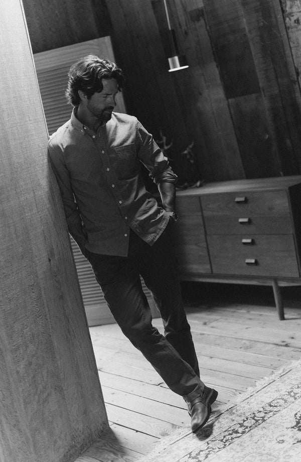 fit model leaning against the wall wearing The Jack in Washed Indigo Chambray