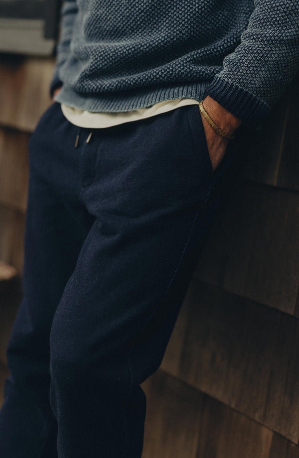fit model leaning against the wall wearing The Sunset Pant in Rinsed Indigo Terry