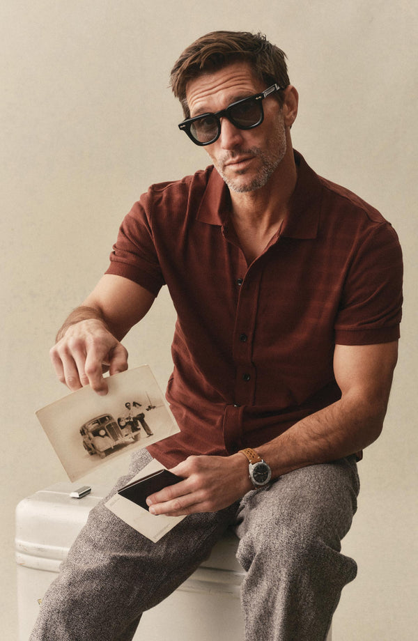 fit model sitting wearing The Bywater Polo in Burgundy Knit Stripe
