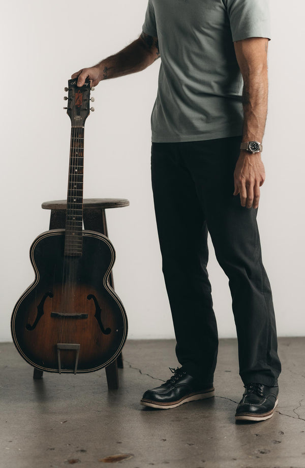 A pair of Foundation Pants folded on a black background, showing the back pocket.