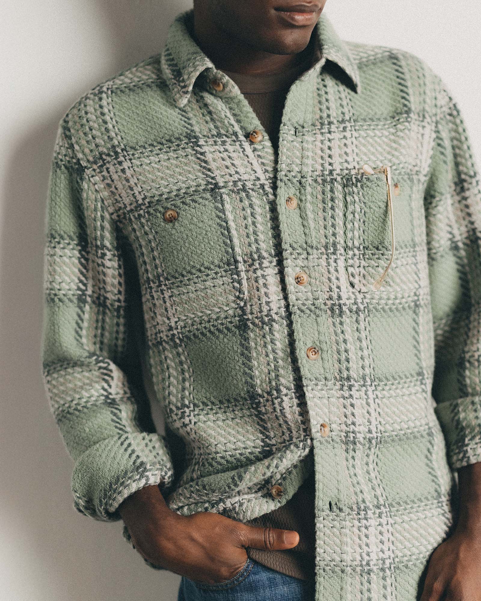fit model leaning against the wall wearing The Cutter Overshirt in Sage Plaid, Wovens by Taylor Stitch