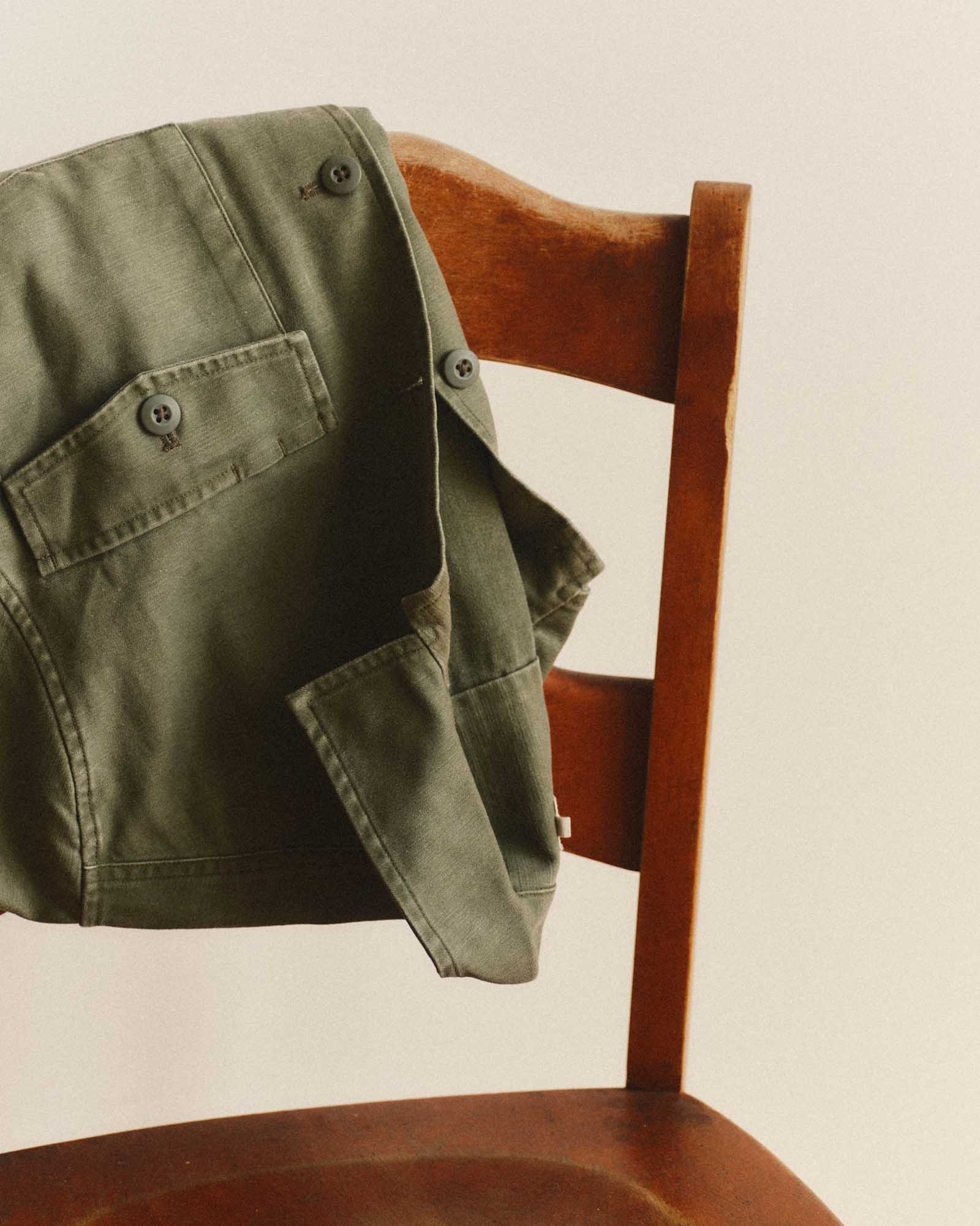 editorial image of The Short Sleeve Surplus Shirt in Field Olive Reverse Sateen on a chair, Wovens by Taylor Stitch