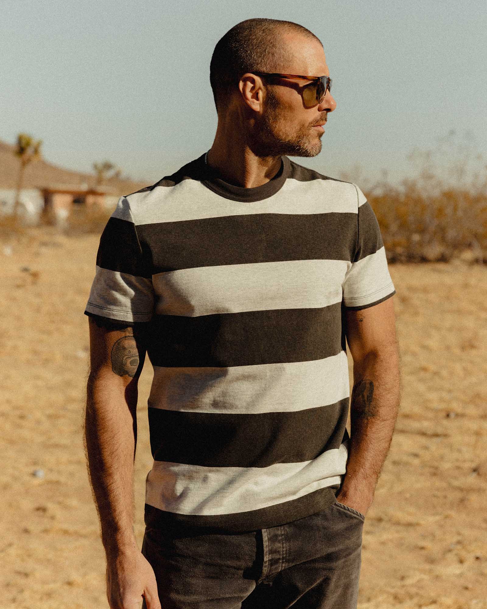 fit model posing in The Organic Cotton Shop Tee in Faded Black Stripe, Knits by Taylor Stitch