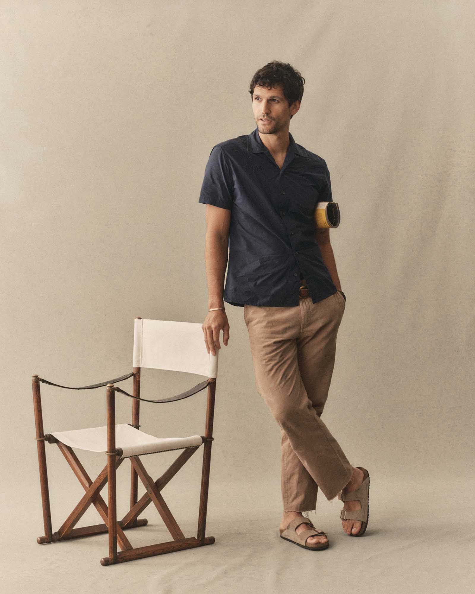 fit model leaning against a chair wearing The Davis Shirt in Navy Floral Embroidery, Wovens by Taylor Stitch