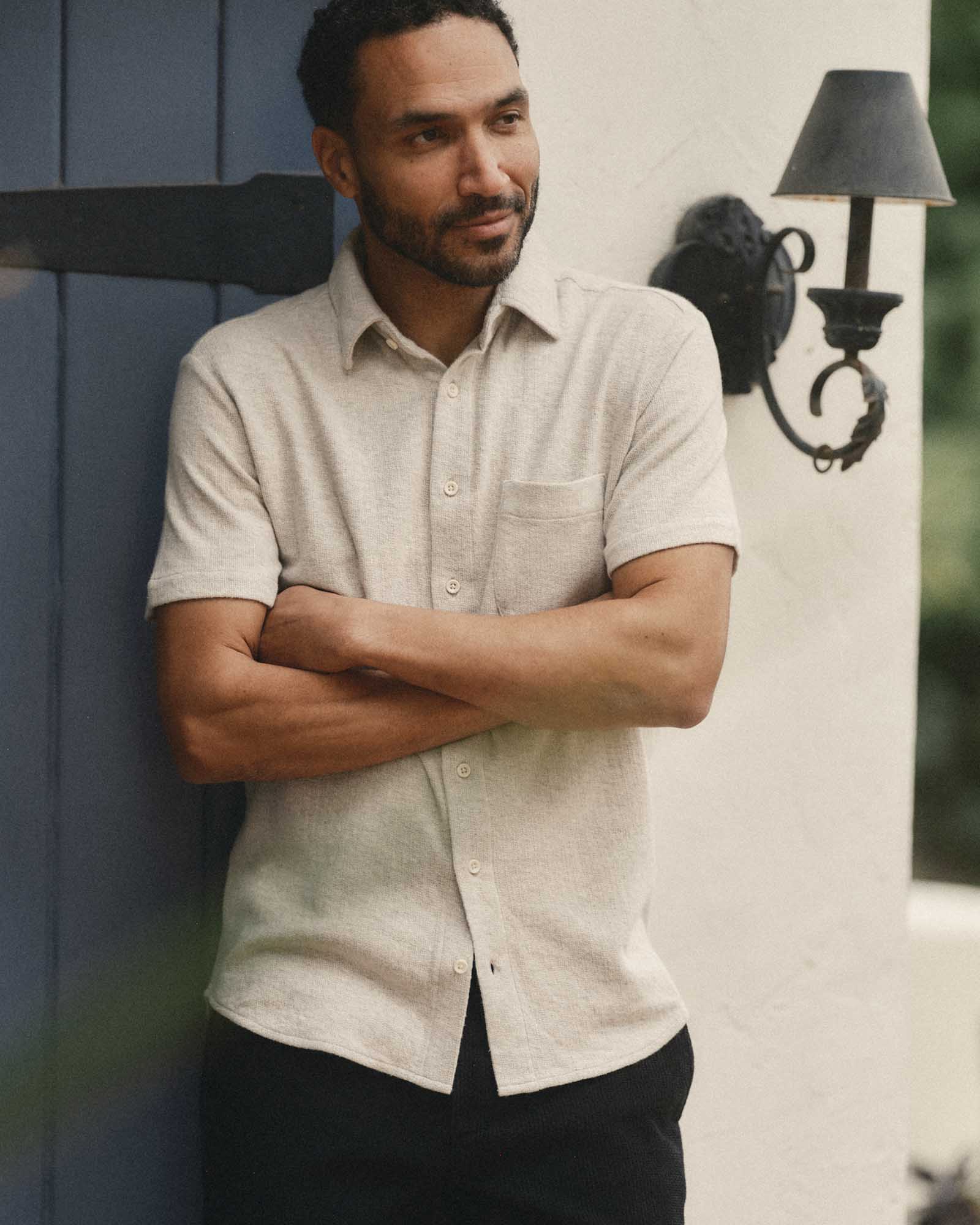 fit model leaning against the wall wearing The Short Sleeve California in Heather Oat Double Knit, Knits by Taylor Stitch