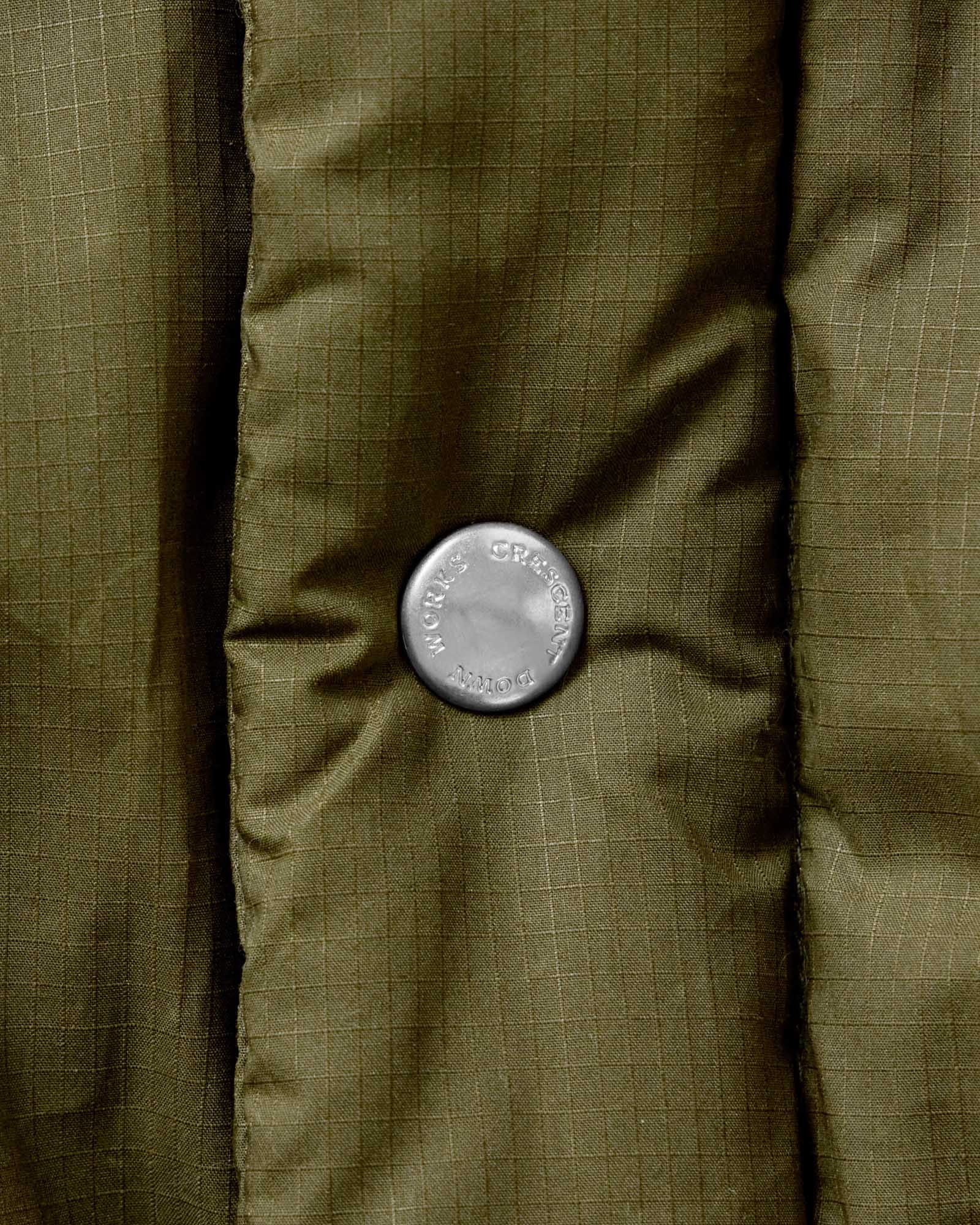 material shot of the buttons on The Down Sweater in Olive Waxed Ripstop, Outerwear by Taylor Stitch