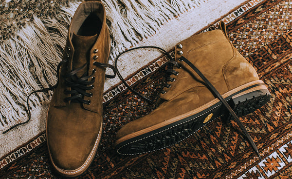 A paid of suede boots tossed on a red rug.