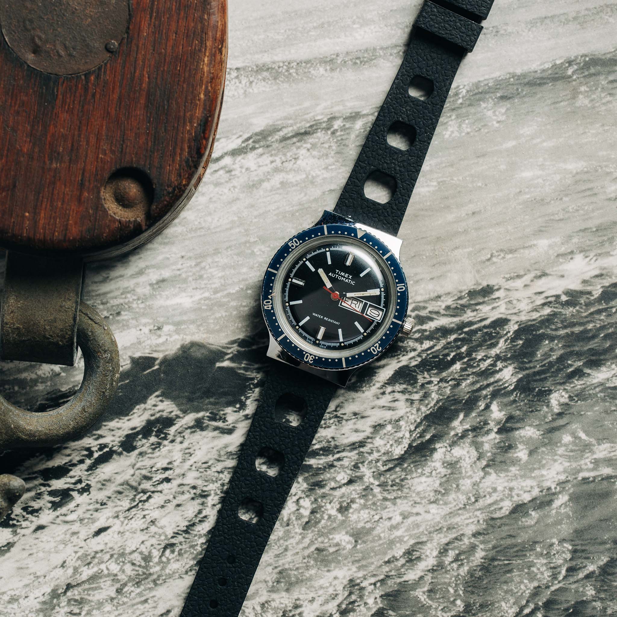 flatlay of the 1978 Timex Viscount M109 on a black and white photo of the ocean, Accessories by Taylor Stitch